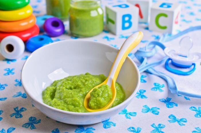 Green mash in the small bowl is on the background of children's toys