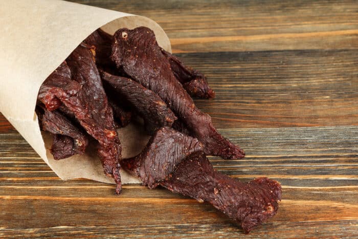 Beef jerky on a wooden board close-up.