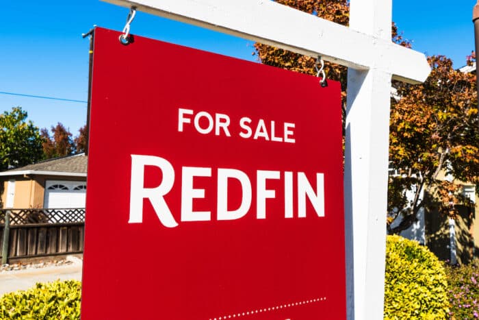 Redfin sign posted in front of a house for sale.