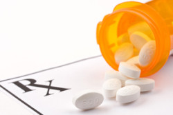 Picture of prescription drug bottle spilling white pills.