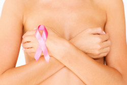 breast cancer survivor holds pink ribbon.