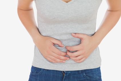 Woman in casuals suffering from stomach ache against white background