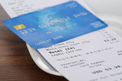Close-up Of Credit Card On Shopping Receipt On Wooden Table