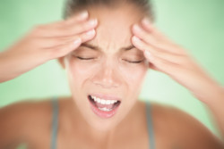 Woman having a migraine / headache holding her head in pain and stress. 