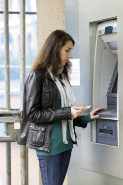The girl draws out money in a cash ATM