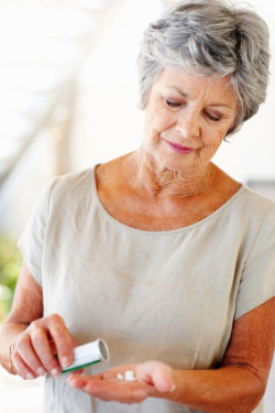 Portrait of senior woman pouring pills out of bottle