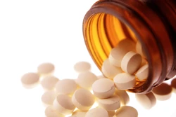 Pills spilling out on white background