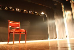 Red chair on empty stage lighted with spotlights