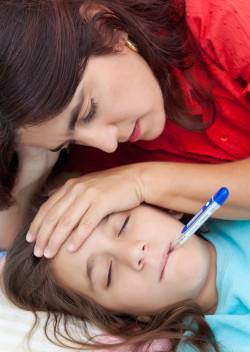 Latin mother checking the temperature of her sick daughter who has a thermometer in her mouth