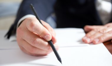 Businessman's hand signing papers. Lawyer, realtor, businessman sign documents on white background.