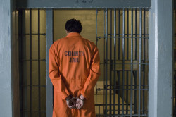 Rear view of a criminal in handcuffs going inside the jail