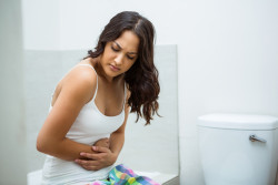 Young woman having stomach pain in bathroom at home