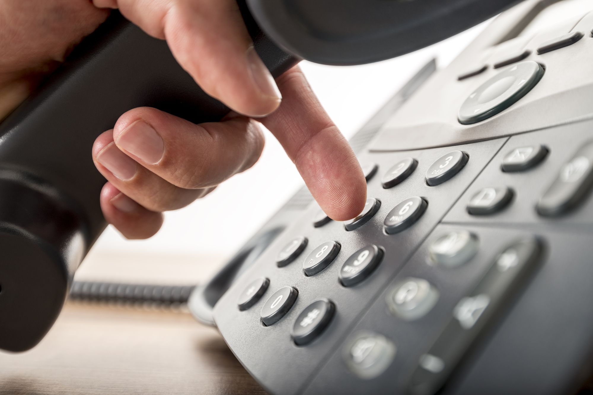 Closeup of dialing a telephone number on a black landline telephone. Conceptual of global communication, business support and customer care.