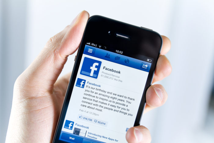 Kiev, Ukraine - February 08, 2012: A man holding Apple iPhone4 with a Facebook application on the screen.