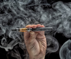Hand holding an electronic cigarette over a dark background