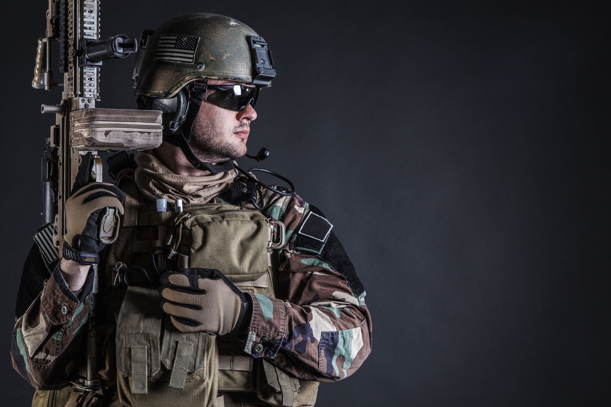 United states Marine Corps special operations command Marsoc raider with weapon. Studio shot of Marine Special Operator half-turning black background