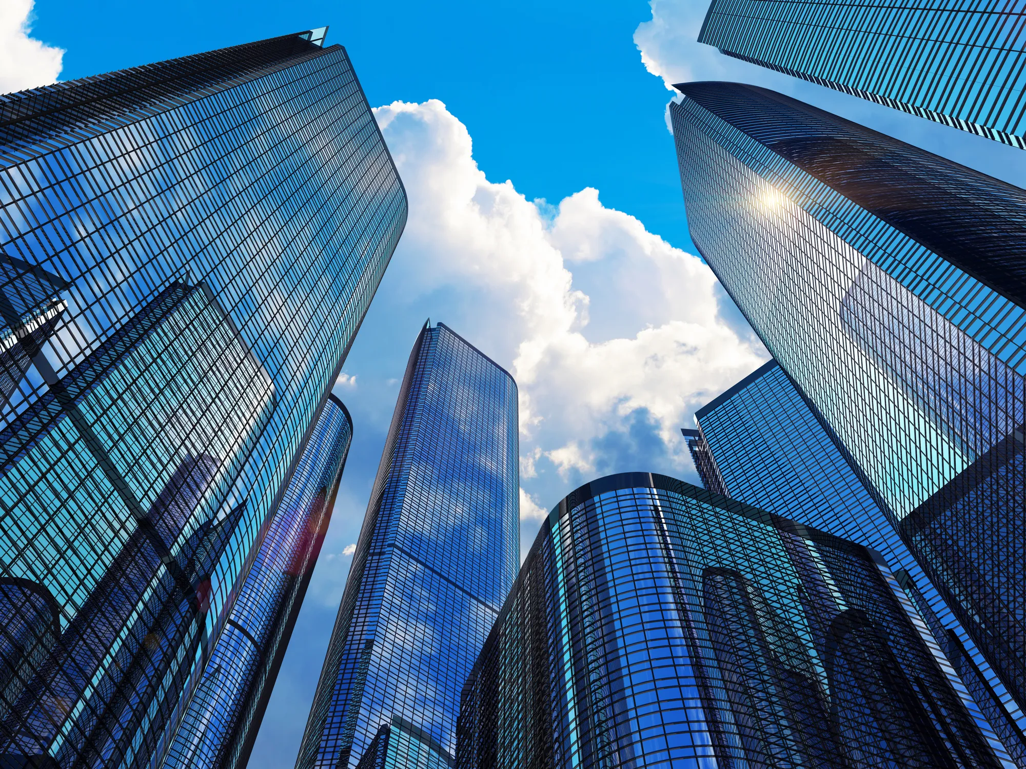 Downtown corporate business district architecture concept: glass reflective office buildings skyscrapers against blue sky with clouds and sun light