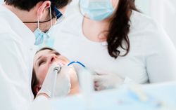 Dentist treating woman patient using drill on her teeth