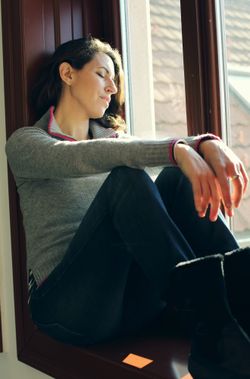 Portrait of beautiful sad woman looking throught the window