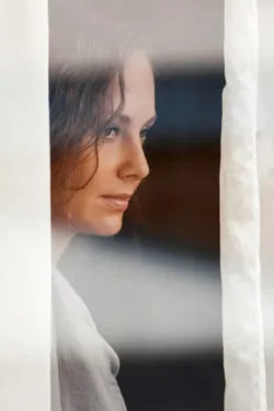 Sad beautiful woman looking through the window