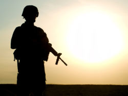 Silhouette of US soldier with rifle against a sunset