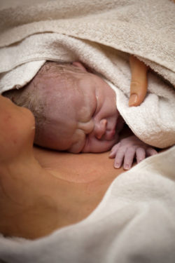 Newborn baby on his mothers arms right after delivery