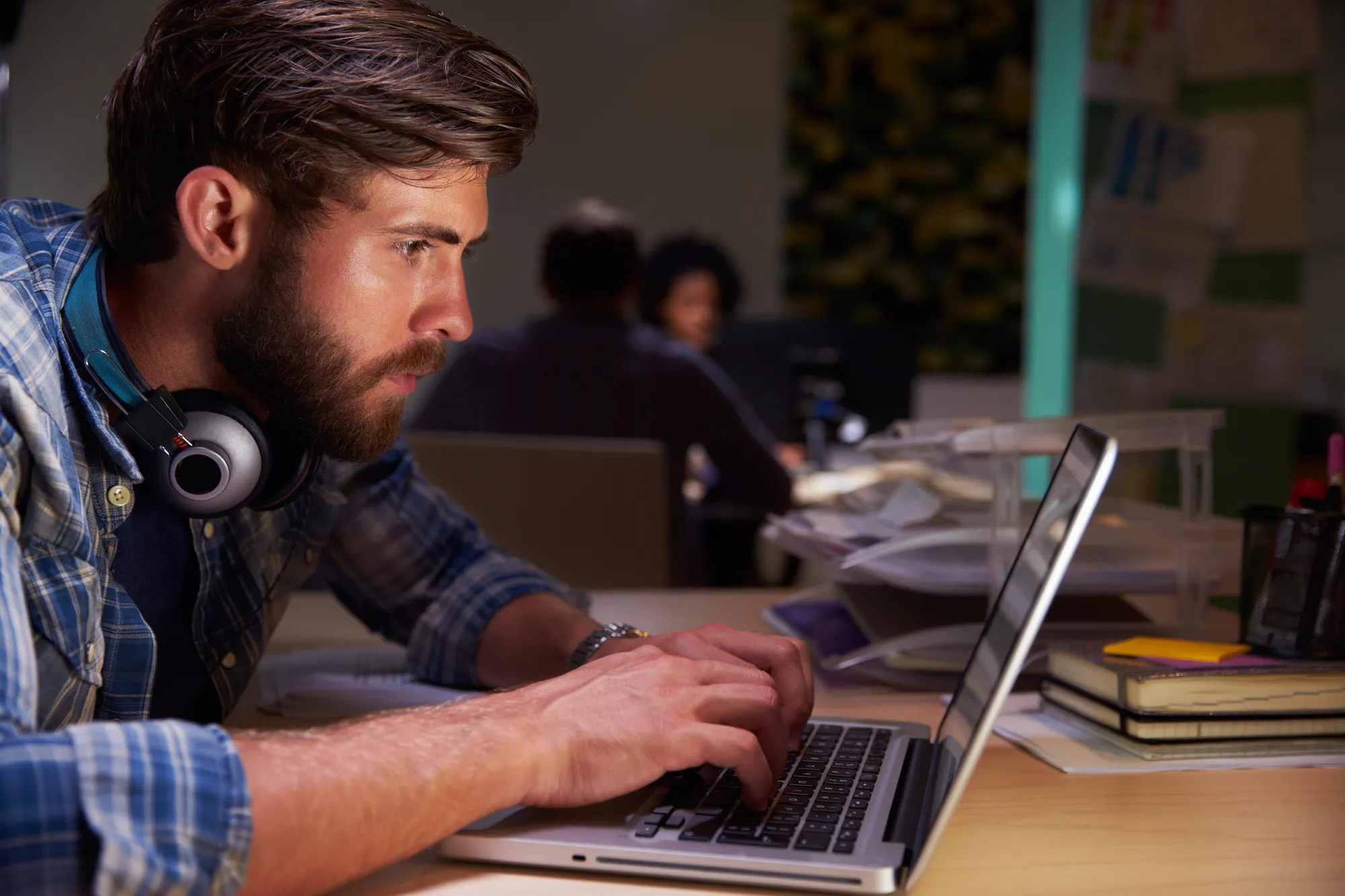 Office Workers At Desks Working Late On Laptops
