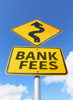 bank fees going up on a yellow and black road sign in a blue sky