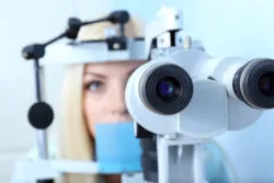 Optometry concept - pretty young woman having her eyes examined by eye doctor