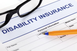 Disability insurance form with glasses and ballpoint pen.