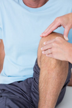 Doctor examining her patient knee in medical office