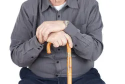 Great detail shot of senior man or elderly sitted and leaning on his cane, focus on hands.