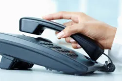 Female hand holding phone receiver over telepnone