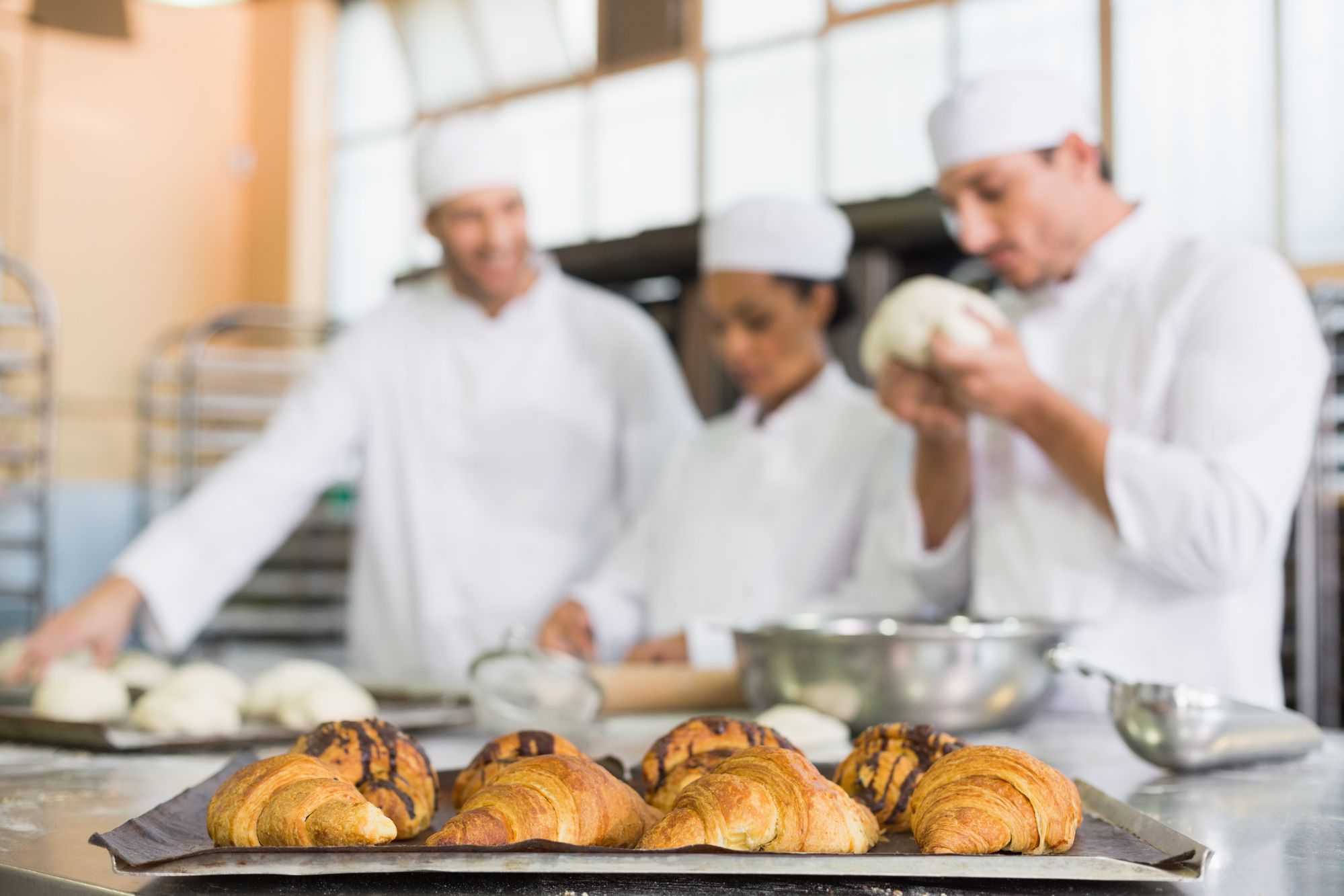 Team of bakers working at counter in the kitchen of the bakery