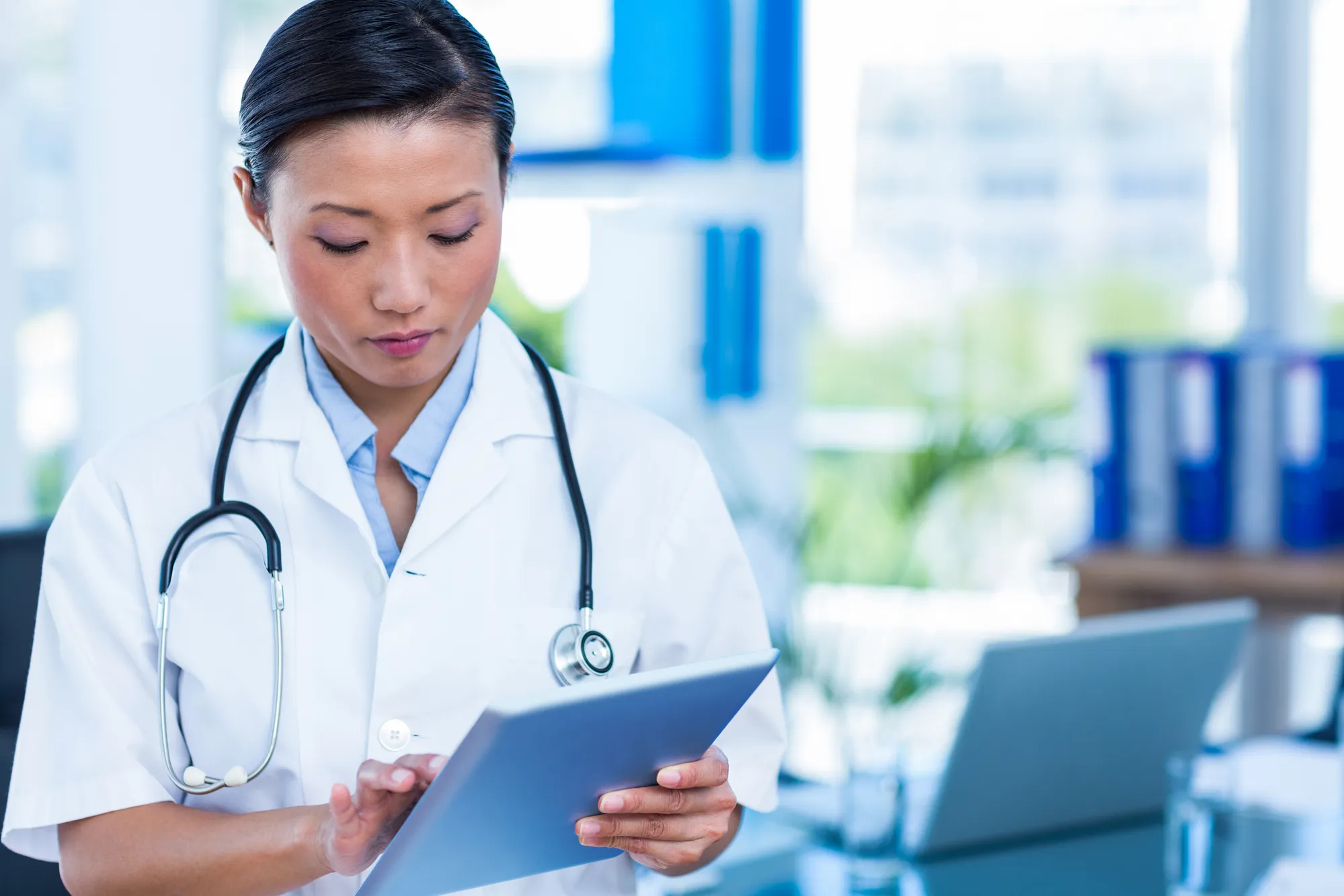 Serious doctor using tablet in medical office
