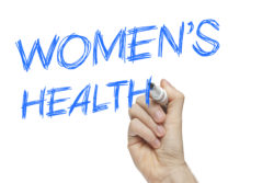 Hand writing women's health on a white board - female issues concept