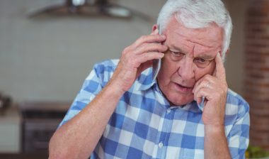 Worried senior man talking on mobile phone at home