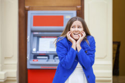Frustrated young woman stands on against ATM in a shopping center