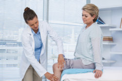 Doctor examining patient knee in clinic