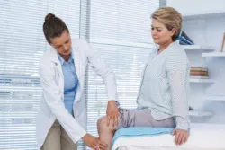 Doctor examining patient knee in clinic