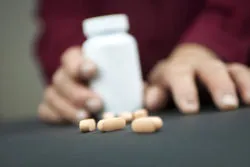 Hands Of Woman Deformed From Rheumatoid Arthritis holding pills