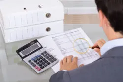 Auditor investigating fraud with magnifying glass.