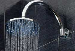 Closeup of chrome shower head with flowing water