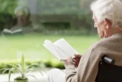 Old man on wheelchair reading a book