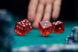 Picture of dice, chips, palm of man in casino on green table, against black background