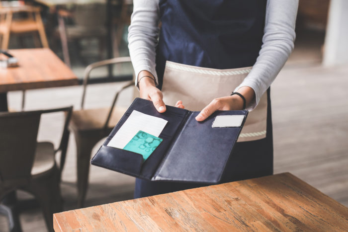 close up of customer hand paying his bills using credit card, assisted by waitress