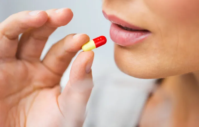 medicine, health care and people concept - close up of woman taking in pill