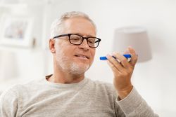 technology, people, lifestyle and communication concept - happy senior man using voice command recorder or calling on smartphone at home