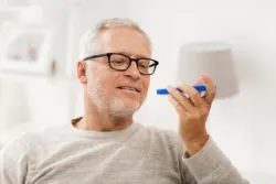 technology, people, lifestyle and communication concept - happy senior man using voice command recorder or calling on smartphone at home