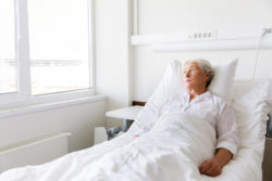 medicine, healthcare and old people concept - sad senior woman lying on bed at hospital ward